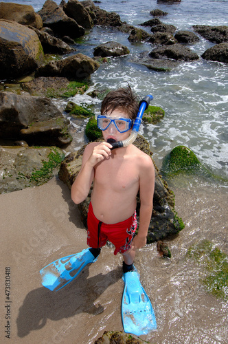 Boy ready to snorkel at ocean edge.
