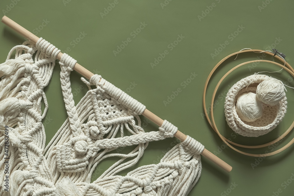 Fototapeta premium Macrame. Handmade macrame weaving and cotton threads on a rustic wooden stick. Scandinavian style in the interior, boho style. Cozy home.recycling, zero waste,eco friendly, small business