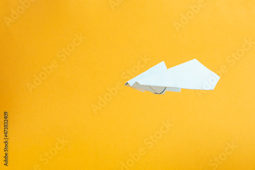 white paper airplane flies on yellow background concept flights and travel