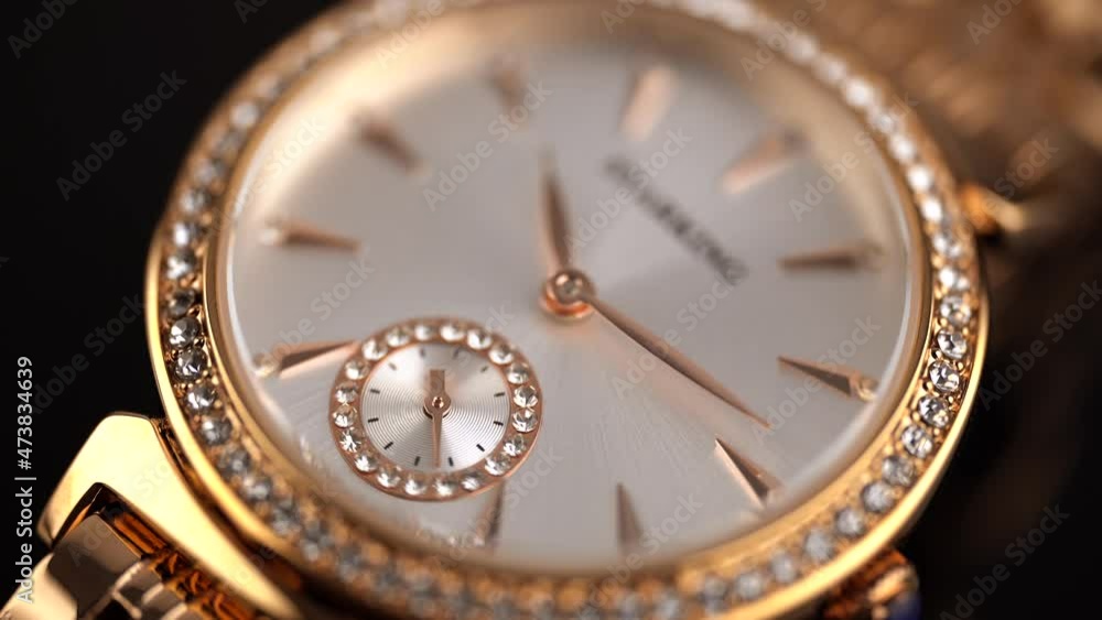 Women's wrist watch. Gold wrist watch with rhinestones and a gold bracelet on a black background. Status accessory. The second hand is accelerated several times. Women's wrist watch. Gold wrist watch with rhinestones and a gold bracelet on a black background. Status accessory. The second hand is accelerated several times.