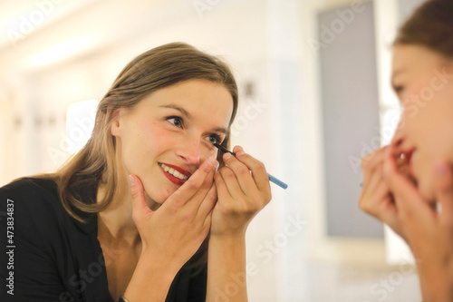 young woman does her makeup in front of the mirror