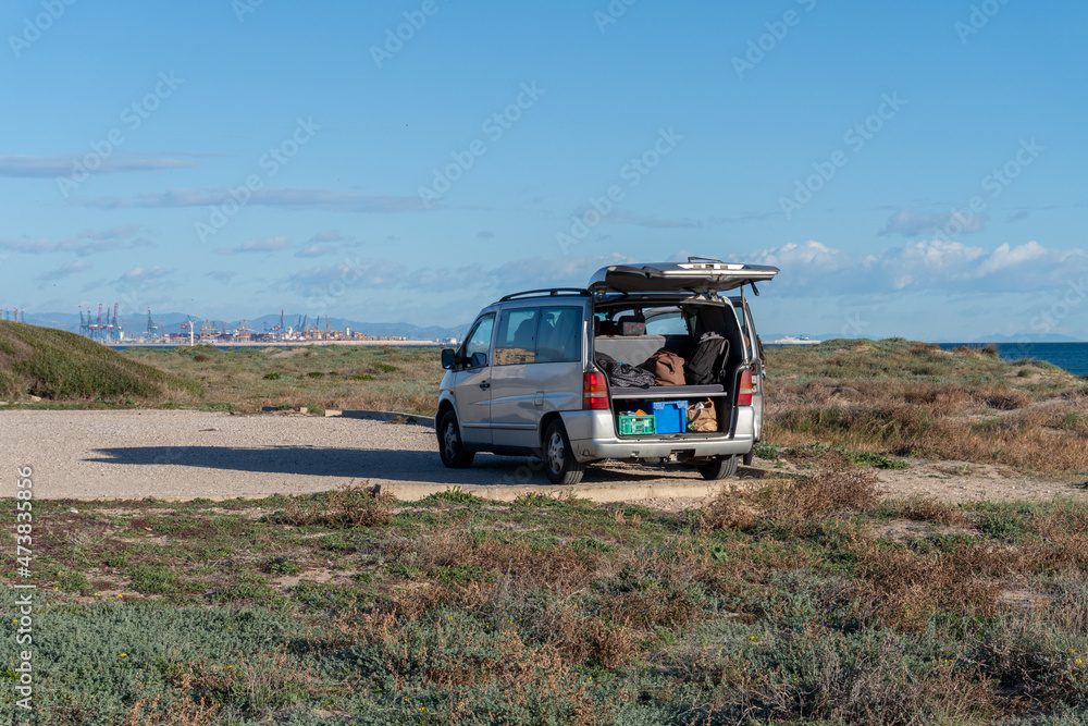 Campervan with the back door open, parked near the sea. Campervan with the back door open, parked near the sea.