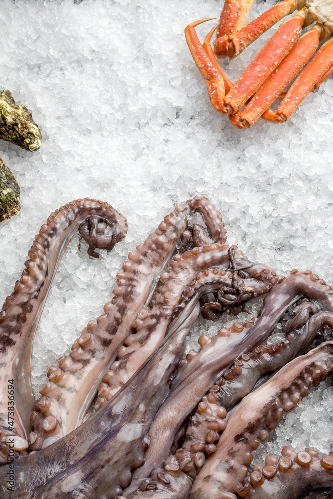 Fototapeta premium fresh octopus tentacles, crab legs and oysters on crushed ice.