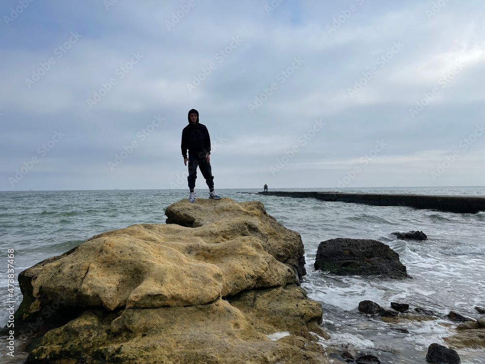 Unrecognizable man standing on a rock on seashore