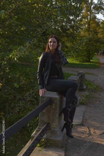 girl in a black leather jacket and black jeans in an autumn park