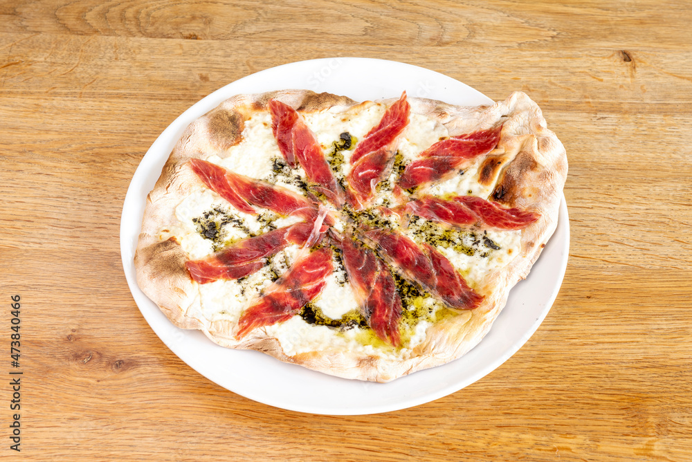 Small homemade pizza with burrata cheese, Spanish acorn ham and olive oil with oregano and basil Small homemade pizza with burrata cheese, Spanish acorn ham and olive oil with oregano and basil