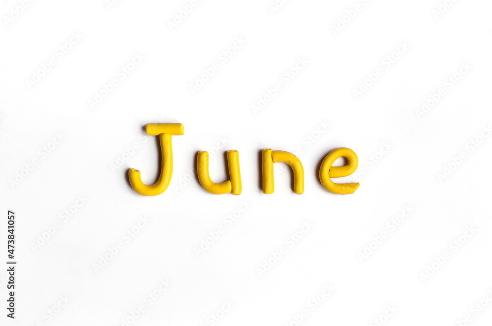 The word June is made of yellow plasticine on a white background The word June is made of yellow plasticine on a white background