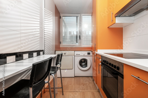Kitchen with orange cabinets, white countertop and white appliances in vacation rental apartment