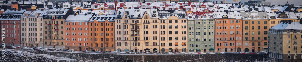 Fototapeta premium Panorama view over snowy and icy apartment buildings a cold and sunny pale winter day with snow in Stockholm