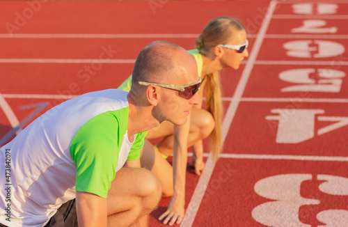 Konstfotografi a man and a woman on the track of the stadium are preparing start of the race