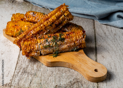 Grilled corn cobs with barbecue spices. Light wooden background.