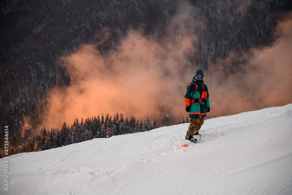 athlete in ski suit stands on snowboard on snow-covered mountain slope athlete in ski suit stands on snowboard on snow-covered mountain slope