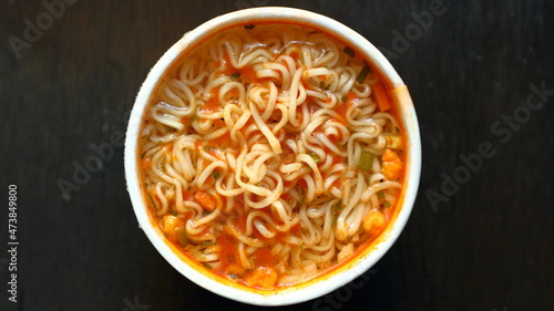 Top view of instant noodles in cup on wooden background