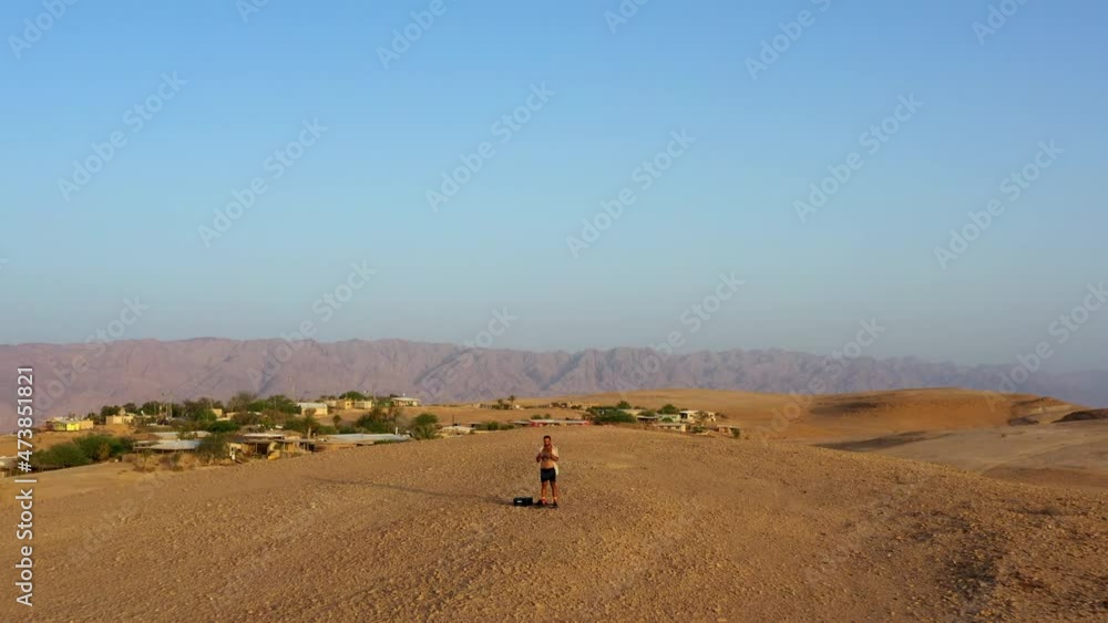 Aerial Scenic Shot Of Structures On Desert Mountain, Drone Flying Backward Man Standing During Vacation - Shaharut, Israel Aerial Scenic Shot Of Structures On Desert Mountain, Drone Flying Backward Man Standing During Vacation - Shaharut, Israel