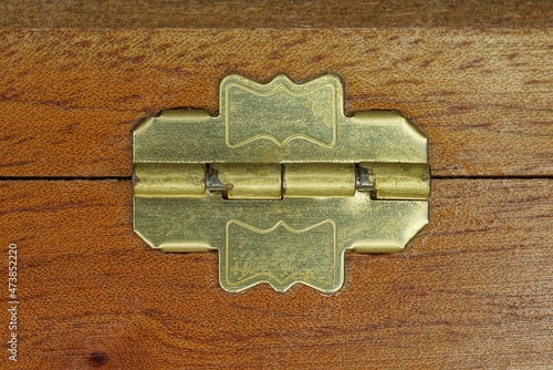one small yellow brass hinge on a brown wooden box board photo