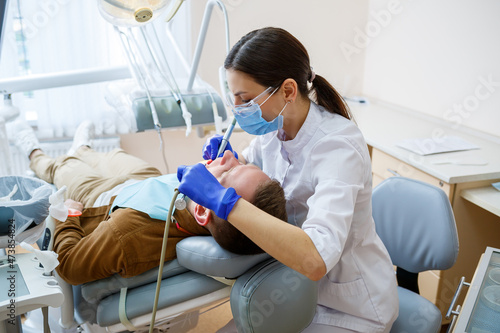 Cuadro en lienzo A female dentist treats tooth decay on a male patient's teeth at a dental clinic during the coronavirus pandemic