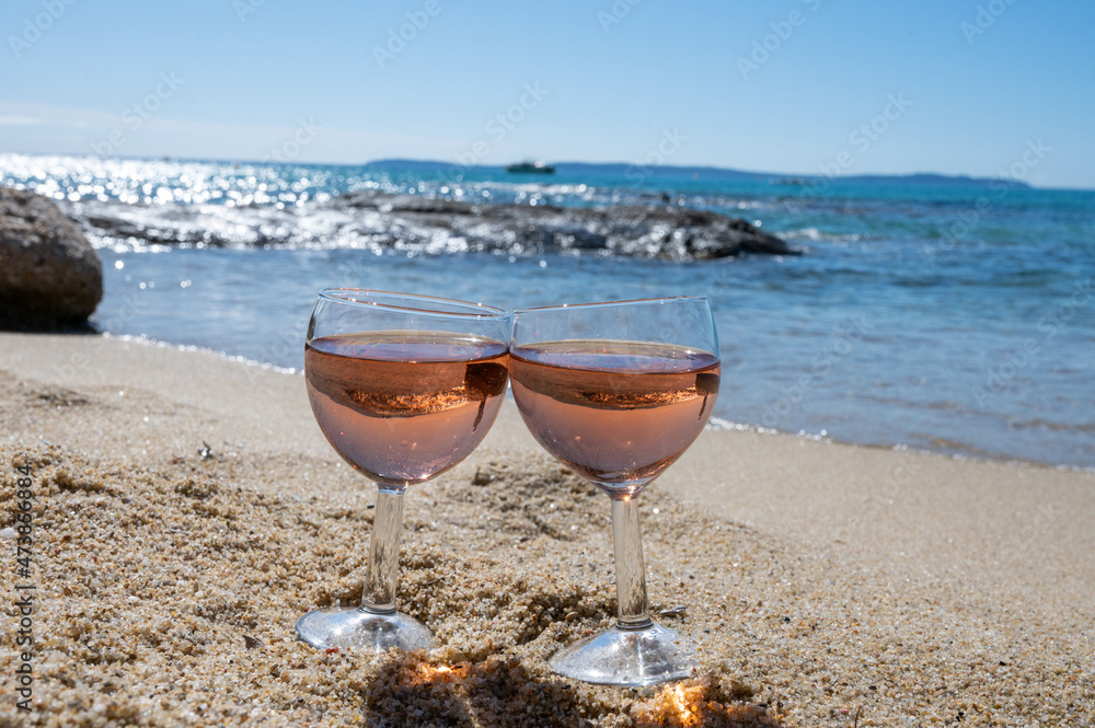 Two glasses of local rose wine on white sandy beach and blue Mediterranean sea on background, near Le Lavandou, Provence, France Two glasses of local rose wine on white sandy beach and blue Mediterranean sea on background, near Le Lavandou, Provence, France