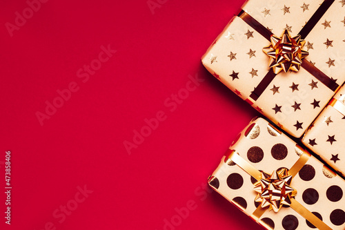 Gift boxes with golden bows on red background. Copy space for your text. Top view. photo