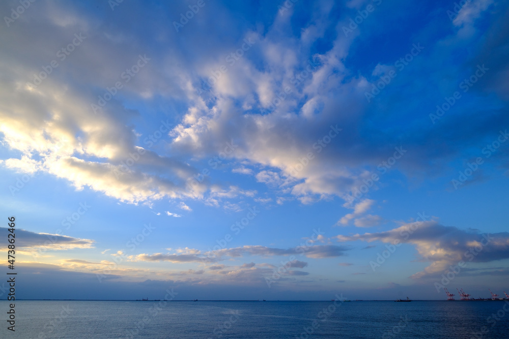 明け方の冬の海。太陽が昇り雲の間から顔を出し、水面はキラキラと輝く。兵庫県芦屋市芦屋浜で撮影。