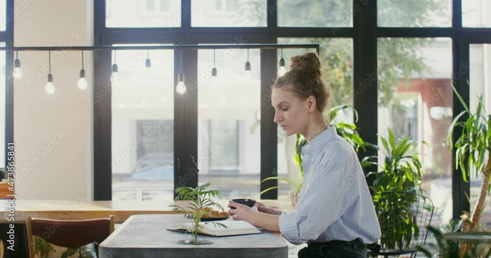 Beautiful woman reads a book and drinks tea while sitting in a coffee shop Beautiful woman reads a book and drinks tea while sitting in a coffee shop