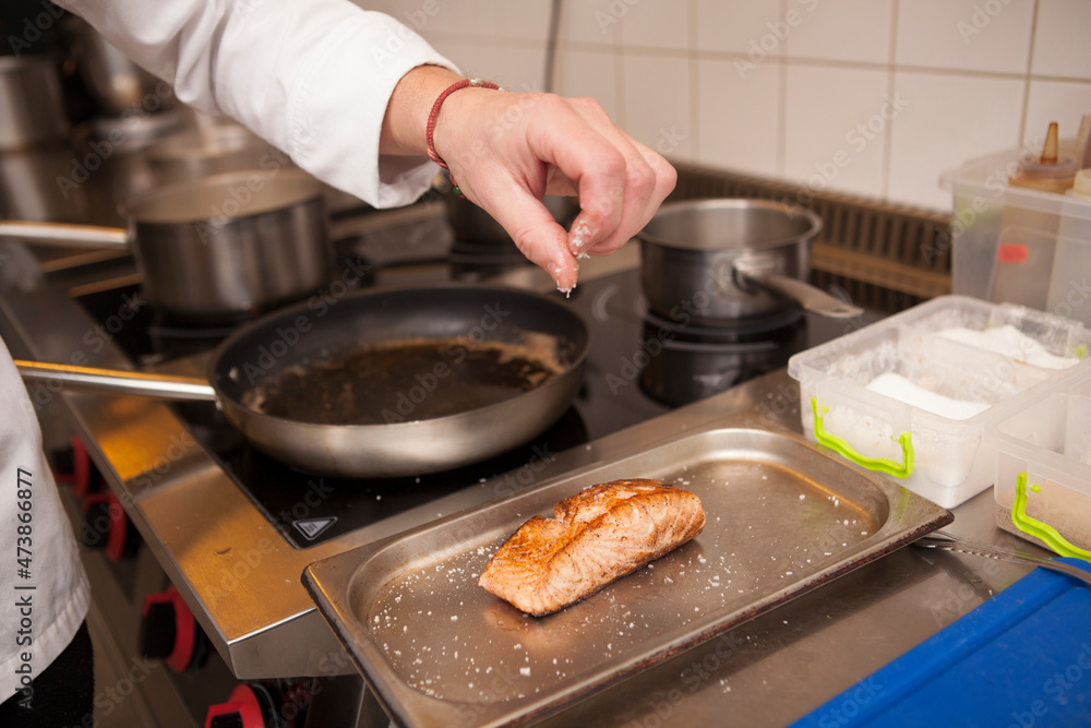 Close up of a chef salting delicious fried salmon Close up of a chef salting delicious fried salmon
