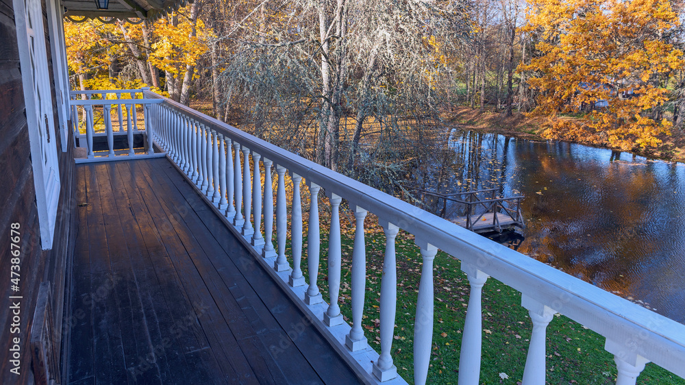 a view from the balcony of an old wooden house to a small overgrown pond surrounded by beautiful autumn trees. Pushkin mountains. Pskov. Russia a view from the balcony of an old wooden house to a small overgrown pond surrounded by beautiful autumn trees. Pushkin mountains. Pskov. Russia