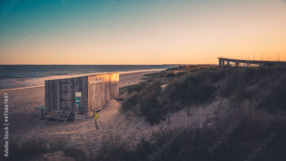 kitesurfing hut at the end of the season at sunrise. bridge of ile de ré in the background.