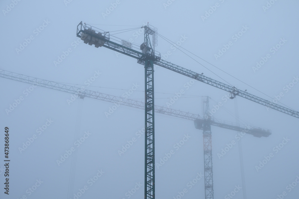 Two cranes working in a foggy afternoon Two cranes working in a foggy afternoon