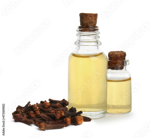 Essential oil and dried cloves on white background