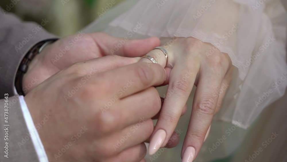Bride and groom exchange wedding rings at ceremony close up. Put on finger jewelry symbol of love and togetherness. Man and woman in love. Marriage outdoors in summer. Bride and groom exchange wedding rings at ceremony close up. Put on finger jewelry symbol of love and togetherness. Man and woman in love. Marriage outdoors in summer.