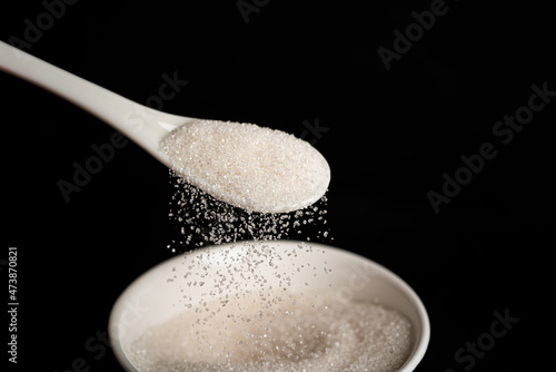Sugar in spoon on a dark background. Sugar bowl.