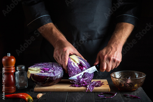 Cook cuts red cabbage with a knife. Cooking vegetable salad in the restaurant kitchen. Vegetable diet idea.