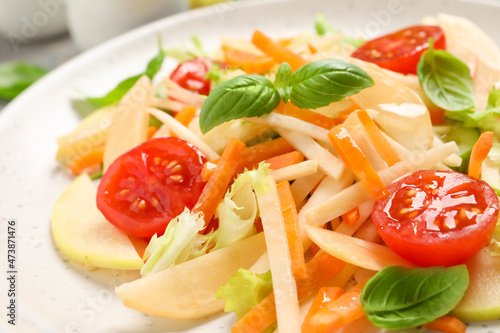 Delicious turnip salad with vegetables and basil on plate, closeup