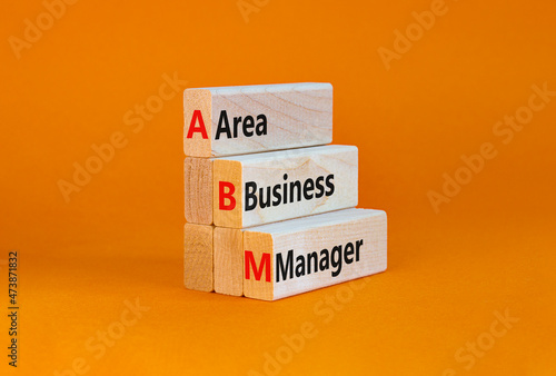 ABM area business manager symbol. Concept words ABM area business manager on wooden blocks. Beautiful orange table, orange background, copy space. Business and ABM area business manager concept.