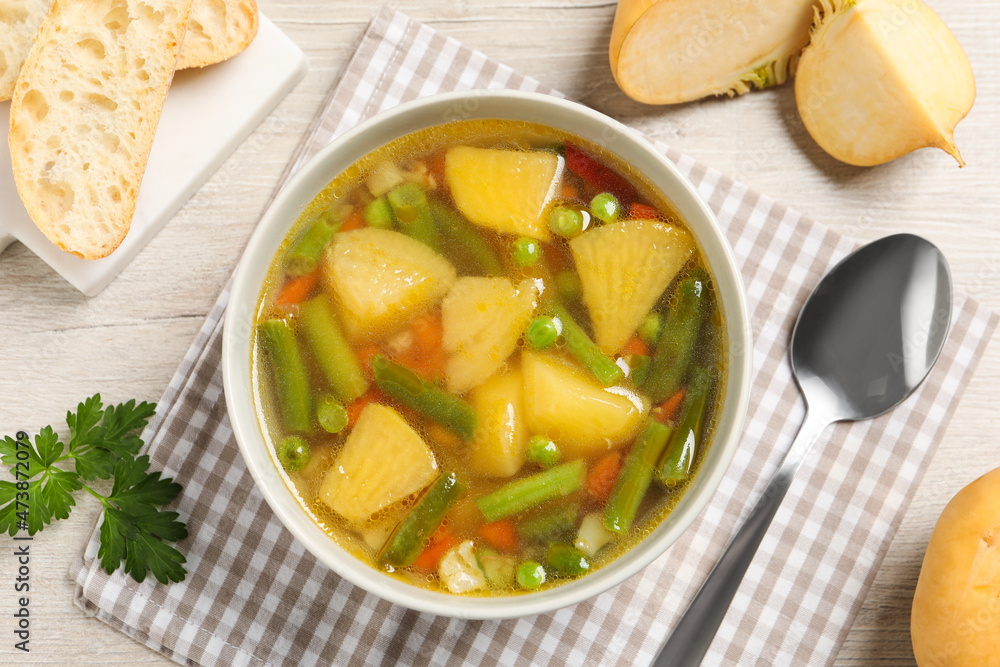 Bowl of delicious turnip soup served on wooden table, flat lay Bowl of delicious turnip soup served on wooden table, flat lay