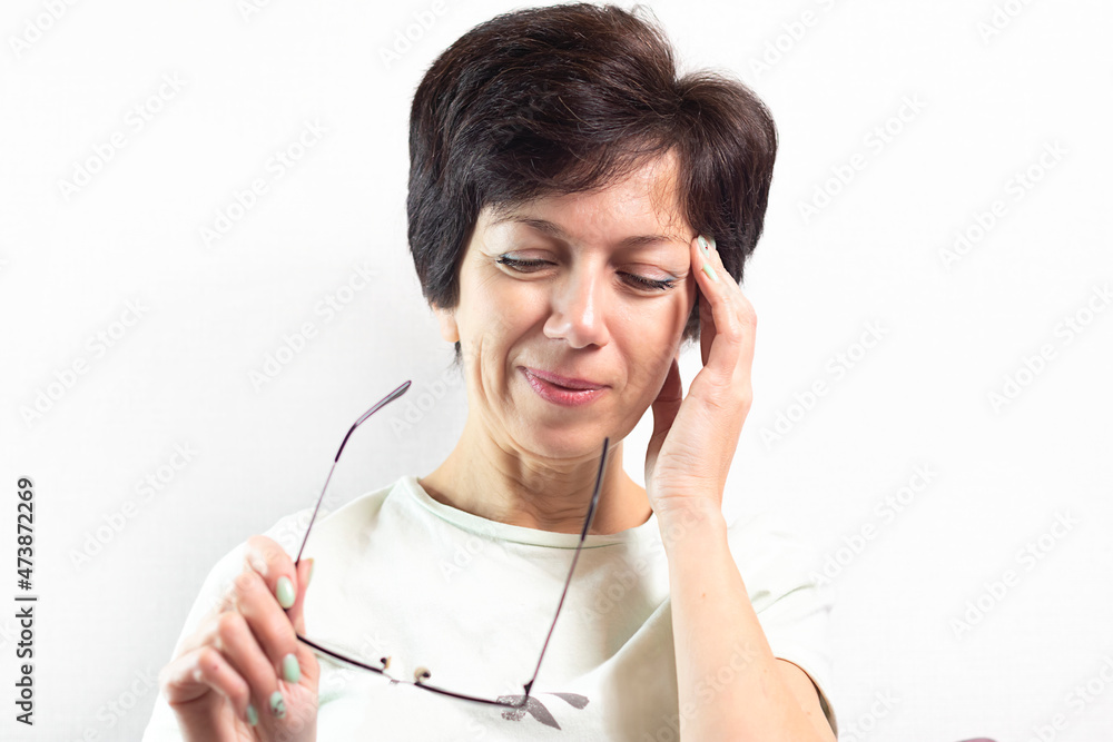 portrait of an adult pretty Jewish woman with eyeglasses in her hands on a light background, soft focus, place for text, fatigue and eye strain, headache portrait of an adult pretty Jewish woman with eyeglasses in her hands on a light background, soft focus, place for text, fatigue and eye strain, headache