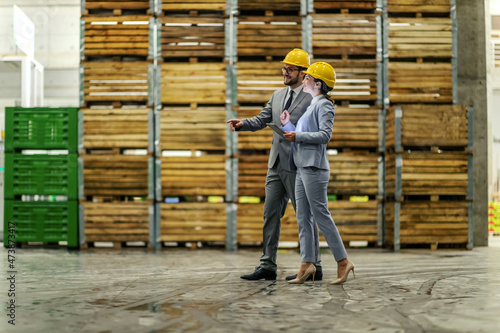 Warehouse business improvement by management supervisions. Business people wear a suit a protective yellow helmet walk in the warehouse. Storage visiting, business owner, small business
