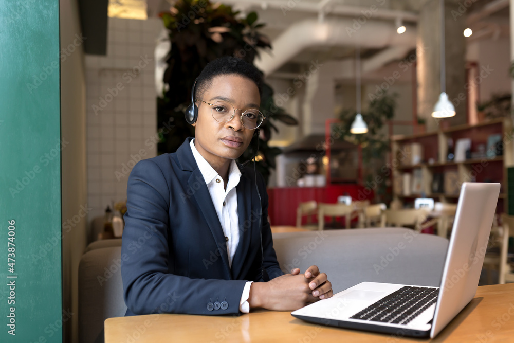Serious African American woman uses a headset for a video call, works in a cafe, during a tourist business trip, business woman focused and thoughtful at work Serious African American woman uses a headset for a video call, works in a cafe, during a tourist business trip, business woman focused and thoughtful at work