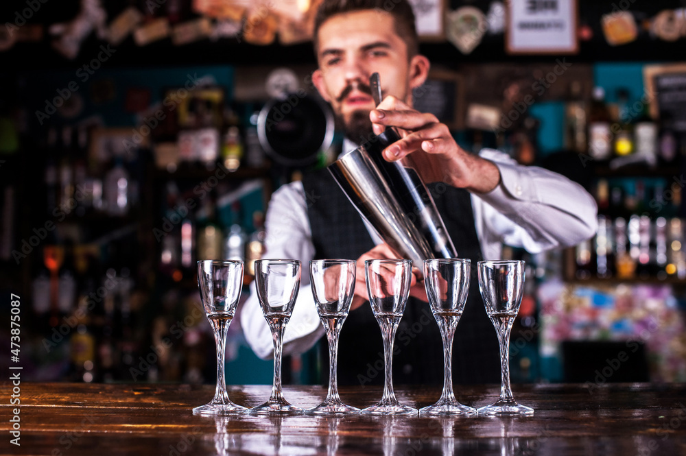 Bearded bartender intensely finishes his creation at bar