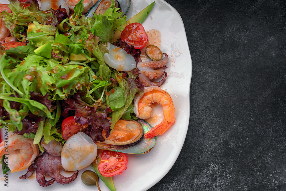 Mix salad with seafood on a dark background