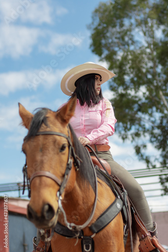 Beautiful cowgirl riding a horse in a ranch