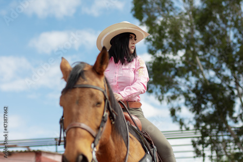 Close up of a beautiful girl riding a horse in a ranch