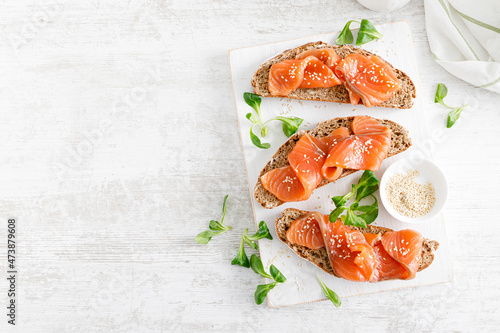 Принти на полотні Whole grain rye bread open sandwiches with salted salmon on a white rustic wooden table