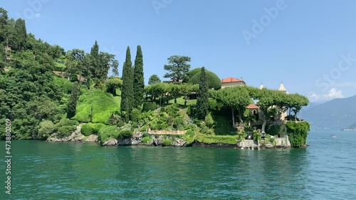 Landscape of Como Lake shore and Villa La Cassinella mansion house. View from moving boat. This villa is beside the famous Villa del Balbianello mansion. Lenno, Tremezzina, Como Lake, Lombardy, Italy.
