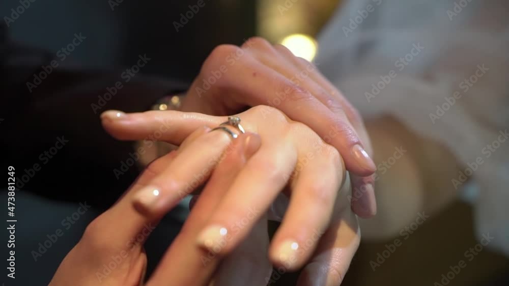 Bride and groom exchange wedding rings at ceremony close up. Put on finger jewelry symbol of love and togetherness. Man and woman in love. Marriage indoors. Bride and groom exchange wedding rings at ceremony close up. Put on finger jewelry symbol of love and togetherness. Man and woman in love. Marriage indoors.