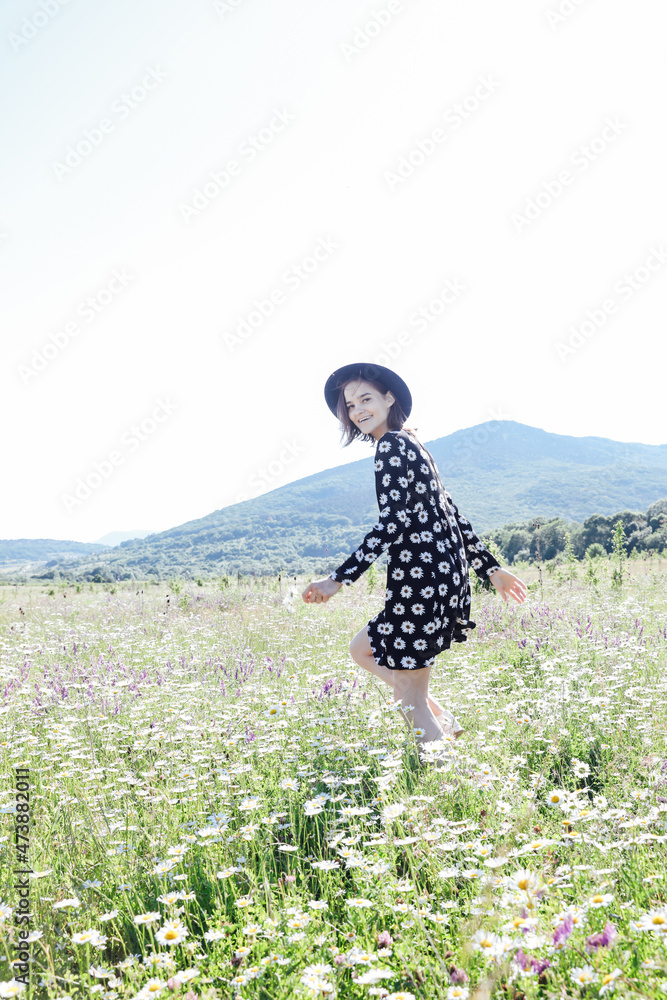 Fototapeta premium a beautiful woman walks through a field of daisies