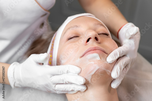 Close-up beautician doctor hand making anti-age procedure, mask and peeling for young attractive female client at beauty clinic. Cosmetologist specialist doing skincare treatment. Health care therapy