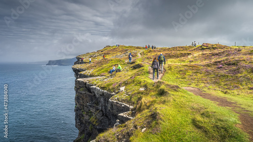 Group of people or tourists hiking and sightseeing iconic Cliffs of Moher, popular tourist attraction, Wild Atlantic Way, County Clare, Ireland photo