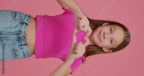 Cute child girl show heart gesture, love sign. Donation and charity concept. Vertical video for social network blog