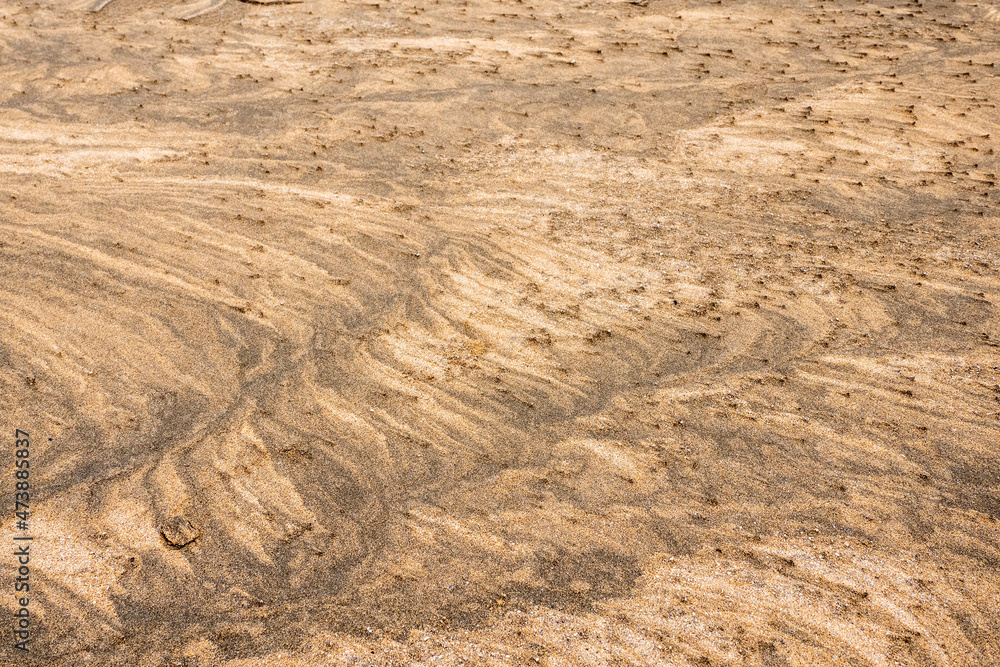 Amazing natural sand pattern made by wind and water on a sandy beach. Unique design for creative purpose. Design background. Random shapes on a dark and light sand surface Amazing natural sand pattern made by wind and water on a sandy beach. Unique design for creative purpose. Design background. Random shapes on a dark and light sand surface